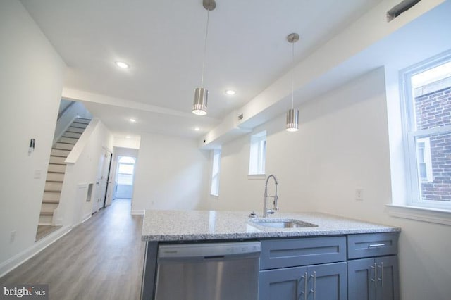 kitchen with light stone countertops, sink, wood-type flooring, dishwasher, and hanging light fixtures