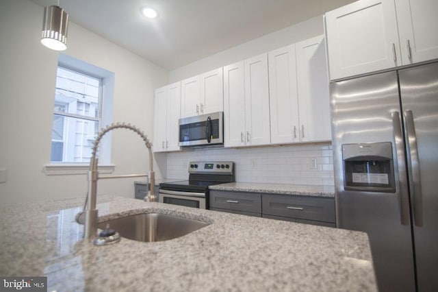 kitchen featuring light stone counters, white cabinets, and stainless steel appliances