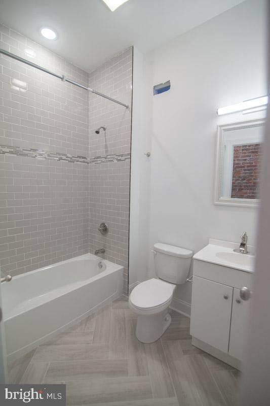 full bathroom with vanity, toilet, and tiled shower / bath combo