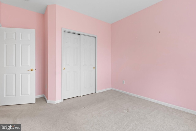 unfurnished bedroom featuring light carpet and a closet