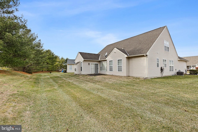 rear view of property with a lawn and cooling unit