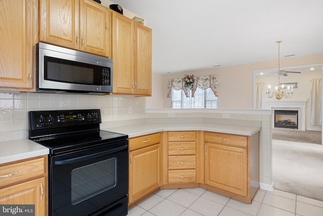 kitchen featuring black electric range oven, light tile patterned floors, light brown cabinetry, and a chandelier