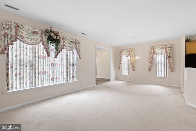 carpeted spare room with an inviting chandelier and a healthy amount of sunlight