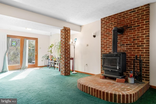 living room featuring carpet, a wood stove, and a textured ceiling