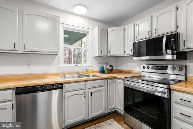 kitchen featuring butcher block counters, sink, stainless steel appliances, and white cabinets