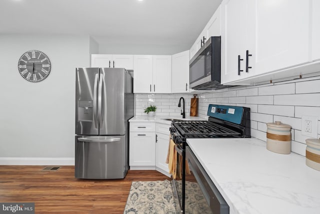 kitchen with decorative backsplash, sink, white cabinets, and appliances with stainless steel finishes