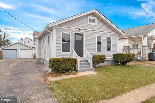 bungalow-style house featuring a garage, an outbuilding, and a front lawn