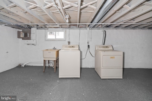 basement featuring washing machine and dryer, sink, and electric panel