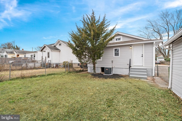 back of property with central AC unit and a yard