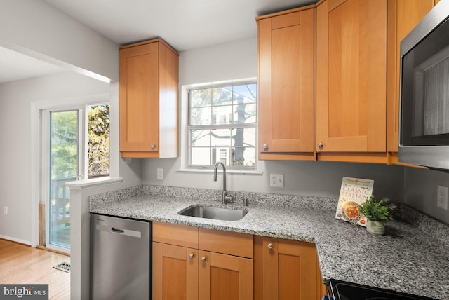 kitchen featuring light stone counters, sink, a wealth of natural light, and appliances with stainless steel finishes