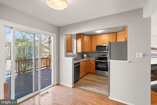 kitchen with sink, light hardwood / wood-style flooring, a textured ceiling, and appliances with stainless steel finishes