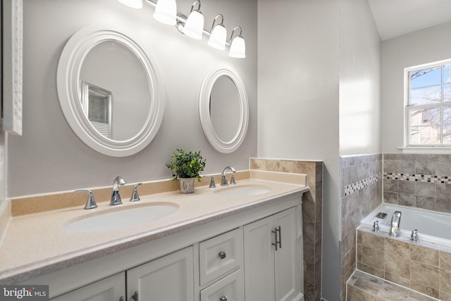 bathroom featuring a relaxing tiled tub and vanity