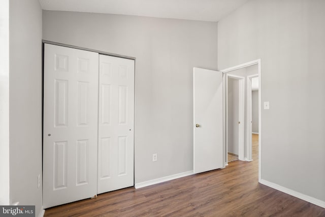 unfurnished bedroom with lofted ceiling, dark hardwood / wood-style floors, and a closet