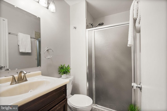 bathroom with a shower with door, vanity, and toilet