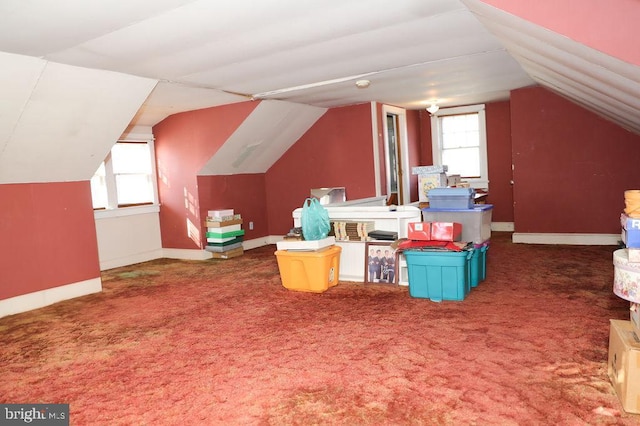 bonus room with dark colored carpet, lofted ceiling, and a wealth of natural light