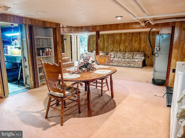 carpeted dining area featuring wood walls