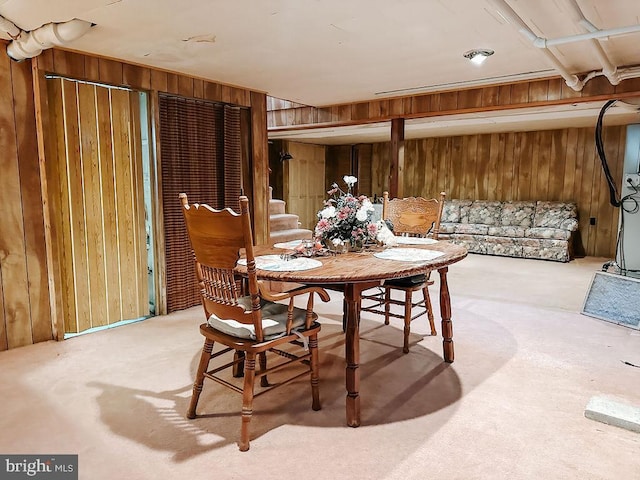 carpeted dining space featuring wood walls