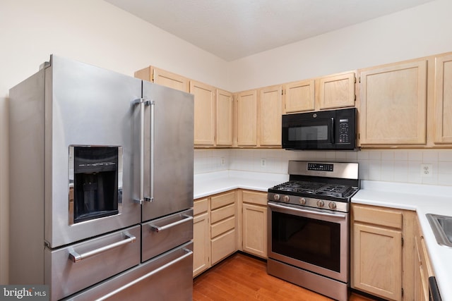 kitchen with light brown cabinetry, backsplash, and appliances with stainless steel finishes