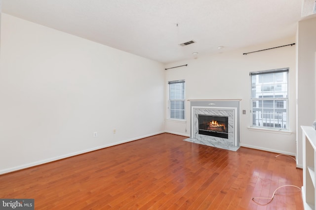 unfurnished living room featuring a premium fireplace and hardwood / wood-style floors