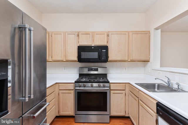 kitchen with light brown cabinetry, decorative backsplash, sink, and appliances with stainless steel finishes