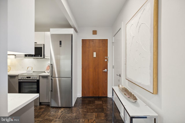 kitchen with dark parquet floors, white cabinets, and stainless steel appliances