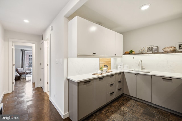 kitchen featuring dark parquet flooring, backsplash, white cabinets, sink, and gray cabinets