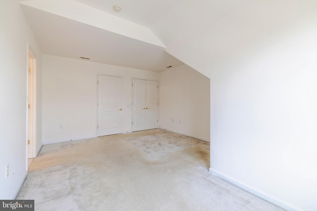 bonus room with light colored carpet and vaulted ceiling