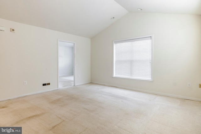 carpeted spare room with vaulted ceiling