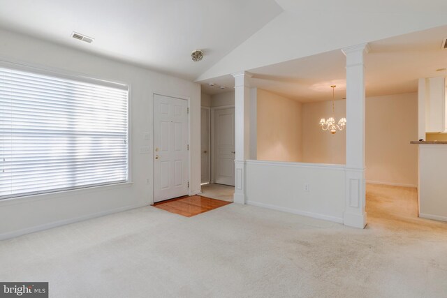 spare room featuring light colored carpet, vaulted ceiling, and a notable chandelier