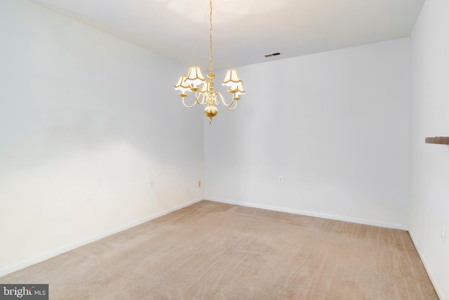 carpeted empty room featuring an inviting chandelier