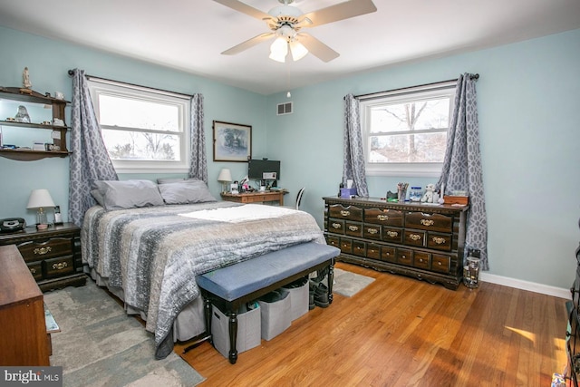 bedroom with multiple windows, ceiling fan, and hardwood / wood-style floors