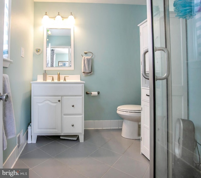 bathroom with tile patterned flooring, vanity, toilet, and a shower with shower door