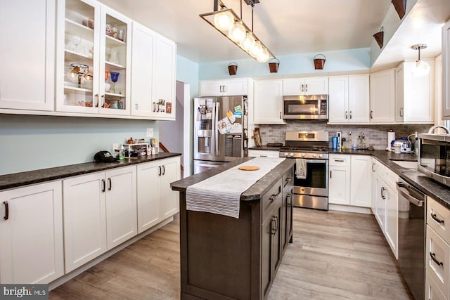 kitchen featuring white cabinets, hanging light fixtures, light hardwood / wood-style floors, a kitchen island, and stainless steel appliances