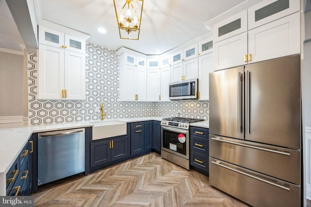 kitchen with white cabinetry, blue cabinets, light stone countertops, and appliances with stainless steel finishes