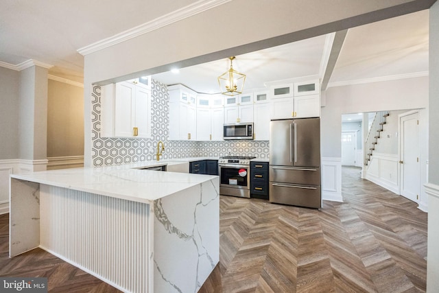 kitchen featuring kitchen peninsula, appliances with stainless steel finishes, white cabinetry, and light stone counters