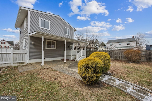 rear view of property with a lawn, covered porch, and a patio