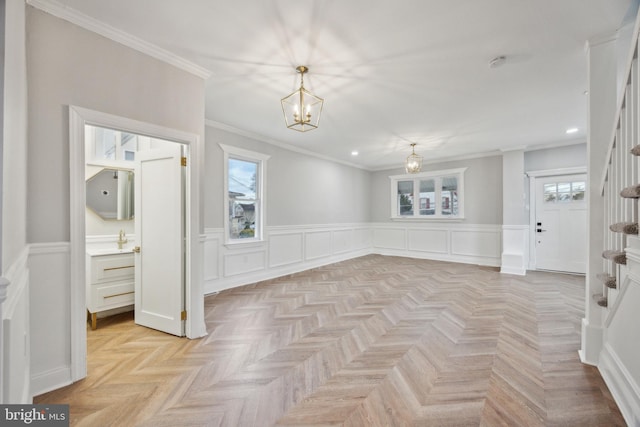 unfurnished room with a wealth of natural light, light parquet floors, a notable chandelier, and ornamental molding