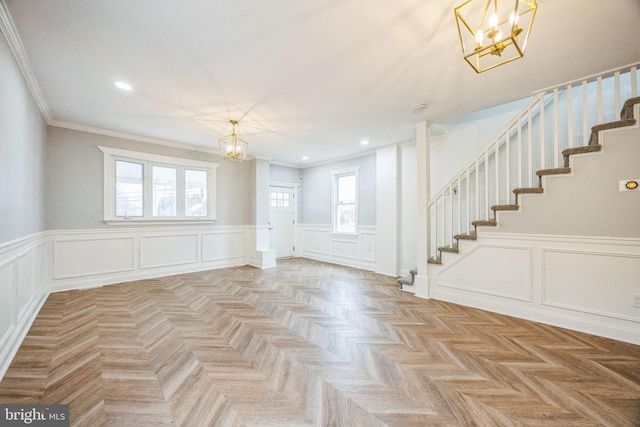 entryway featuring light parquet flooring, ornamental molding, and an inviting chandelier