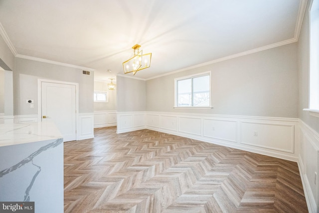 empty room featuring light parquet flooring, an inviting chandelier, and crown molding