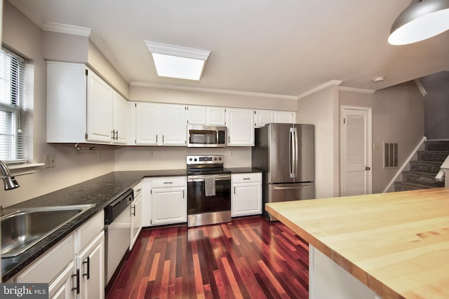 kitchen with butcher block countertops, white cabinetry, sink, and appliances with stainless steel finishes