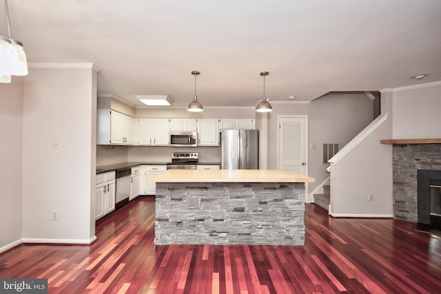 kitchen featuring white cabinets, a center island, stainless steel appliances, and hanging light fixtures