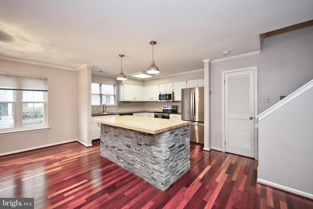 kitchen featuring sink, stainless steel appliances, a kitchen island, pendant lighting, and white cabinets