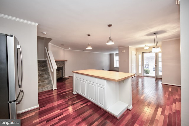 kitchen featuring wood counters, crown molding, white cabinets, a center island, and stainless steel refrigerator