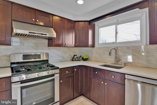 kitchen with under cabinet range hood, stainless steel appliances, a sink, and light countertops