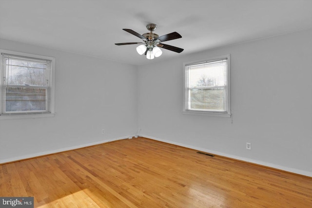 unfurnished room featuring a ceiling fan, visible vents, baseboards, and wood finished floors