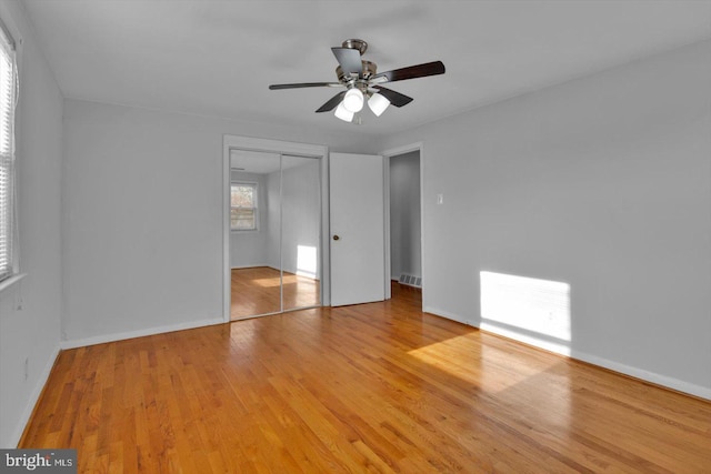 unfurnished bedroom featuring a closet, visible vents, baseboards, and wood finished floors