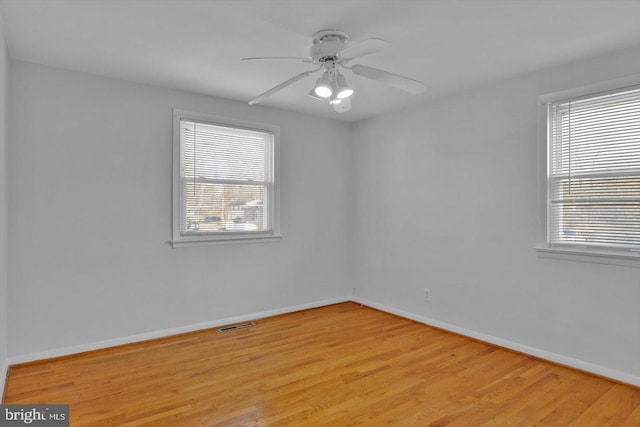 unfurnished room featuring baseboards, visible vents, a ceiling fan, and light wood-style floors