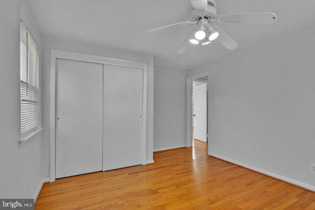 unfurnished bedroom with baseboards, a closet, light wood-style flooring, and a ceiling fan