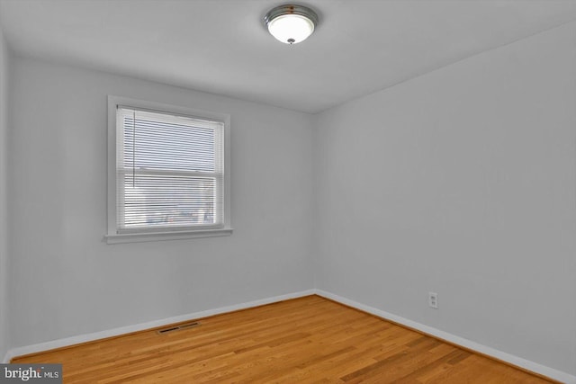 empty room with baseboards, visible vents, and wood finished floors