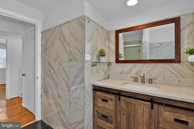 bathroom featuring tile walls, vanity, and wood finished floors